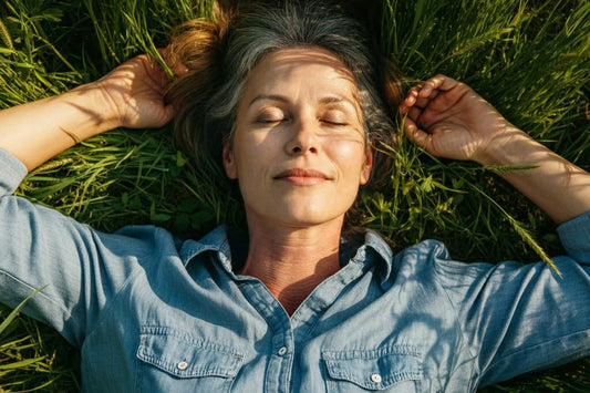 Middle-aged woman relaxing in the grass with her eyes closed, enjoying the outdoors.
